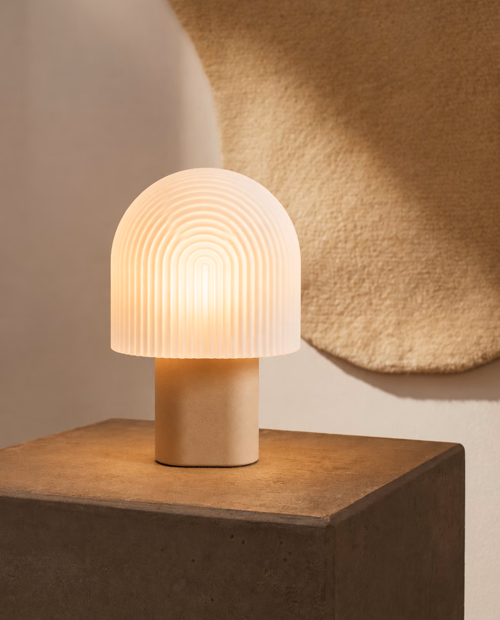 DOMEA table lamp on a dark concrete block in front of a round wool wall hanging